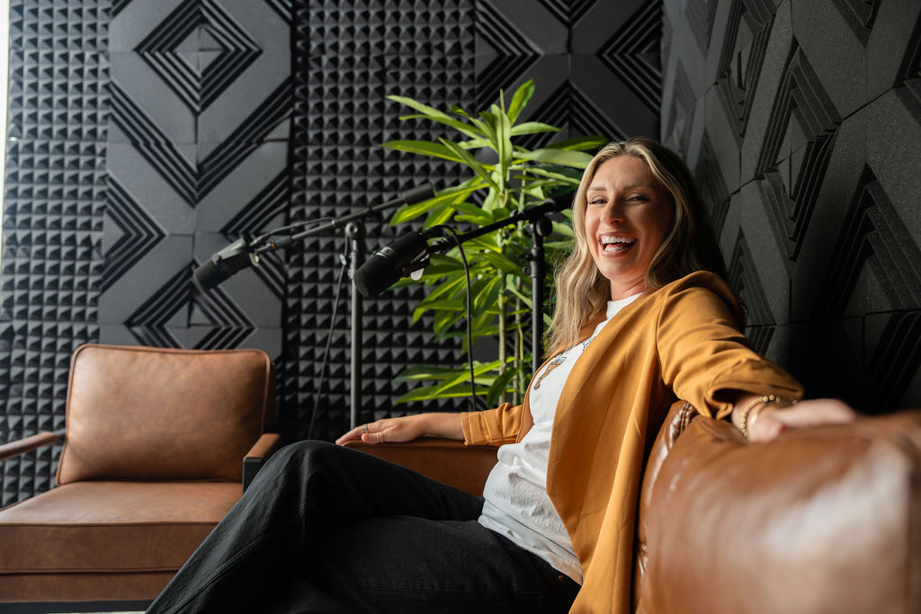 Shelby Khan laughing at the microphone in a podcast studio